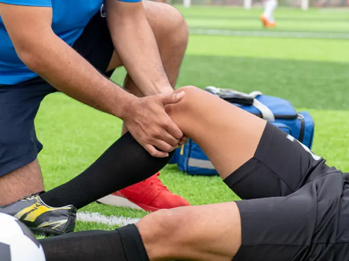 Soccer player nursing another soccer player's injury on field